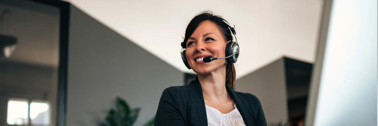 Une conseillÃ¨re souriante en ligne avec un casque micro travaille Ã  son bureau