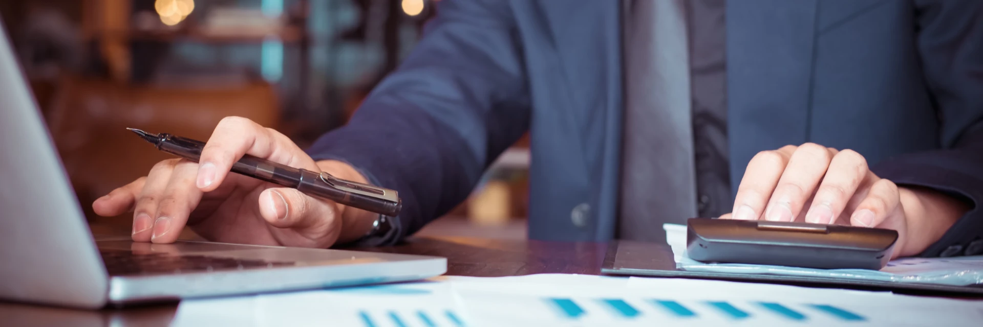 Homme d'affaires en costume utilisant un ordinateur et une calculatrice pour ses analyses