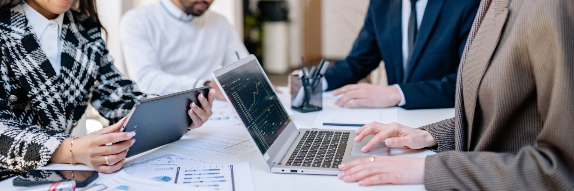 Ã‰quipe de professionnels en rÃ©union analysant des donnÃ©es sur ordinateurs, tablettes et documents.