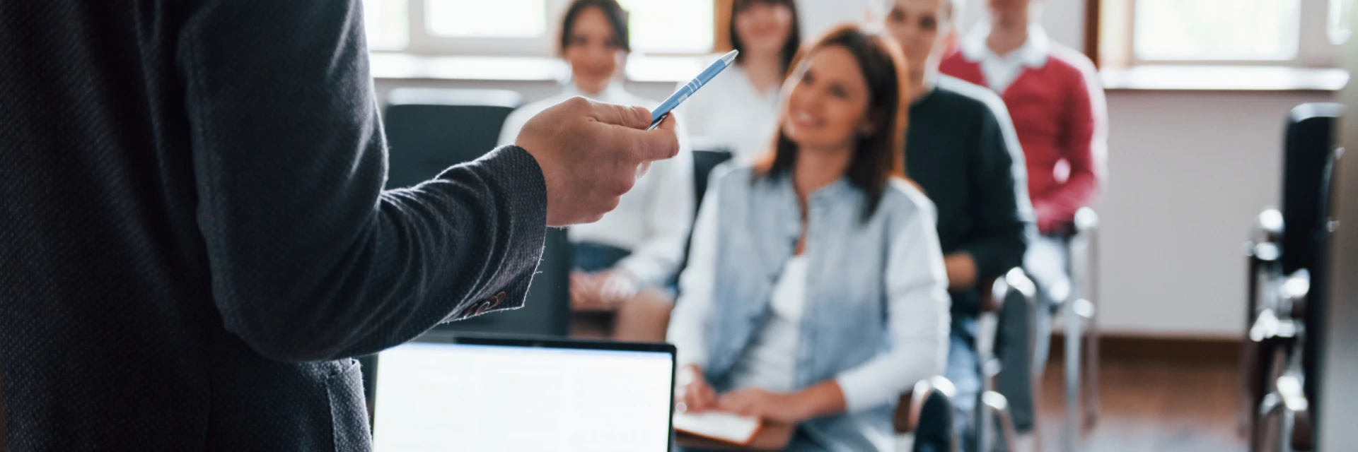 ConfÃ©rencier prÃ©sentant une formation face Ã  une audience attentive en salle de sÃ©minaire.