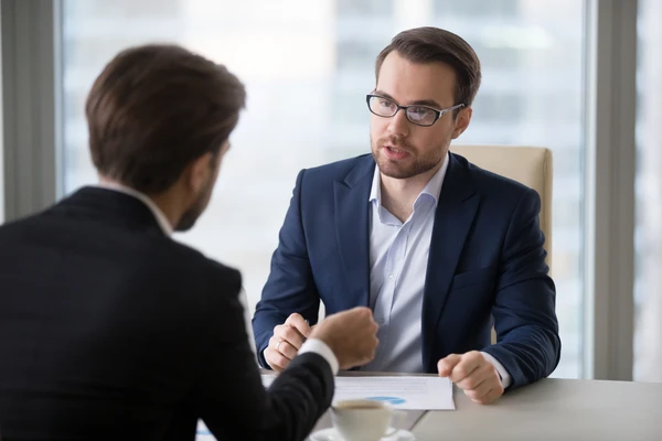 Deux professionnels en costume discutent sérieusement lors d'un rendez-vous d'affaires au bureau.