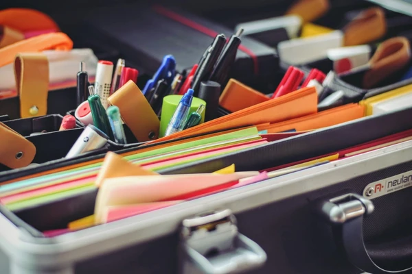 Une mallette ouverte remplie de fournitures de bureau colorées, stylos et dossiers organisés.